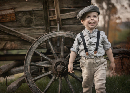Portrait og a little, cute gentleman posing over a wooden carriageの写真素材
