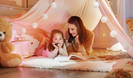 Happy mother reading a novel with her daughterの写真素材