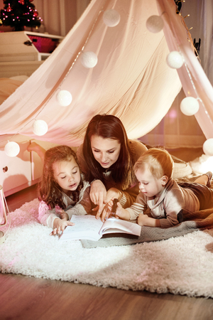 Young mother reading a novel with her childrenの写真素材