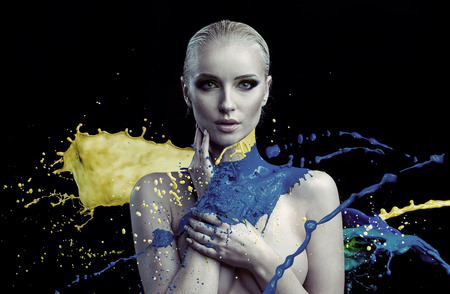 Portrait of colorful paint splashing against a young womanの写真素材