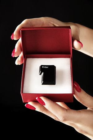 Conceptual photo of an "enter" button in a red gift boxの写真素材