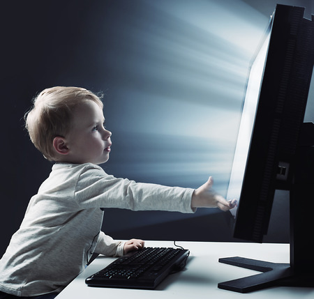 Conceptual portrait of a cute, little boy using a computer - Internt risk symbolの写真素材