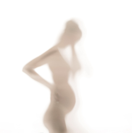 Silhouette of pregnant woman behind the glass wallの写真素材
