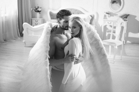 Conceptual portrait of an archangel embracing a beautiful, blond womanの写真素材