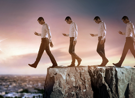 conceptual portrait of a young, successful businessman falling down from the cliffの写真素材