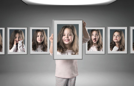 Little, cheerful girl among lots of her different portraitsの写真素材