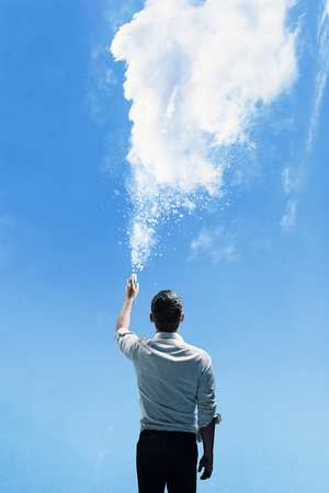 Conceptual picture of a man sprinkling a dense cloudの写真素材