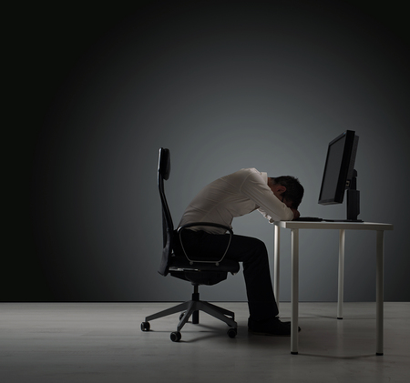 Exhausted businessman having a nap on the deskの写真素材