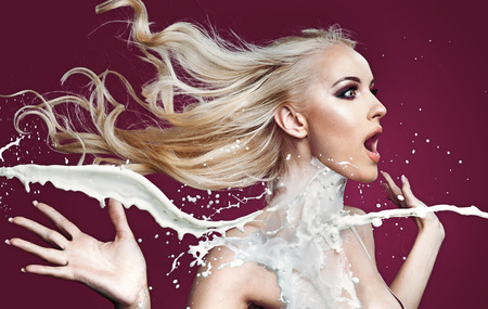Amazed blond woman being poured with white paintの写真素材