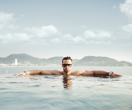 Portrait of a serious man relaxing in a tropical poolの写真素材
