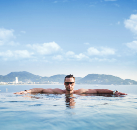 Portrait of a serious man relaxing in a tropical poolの写真素材