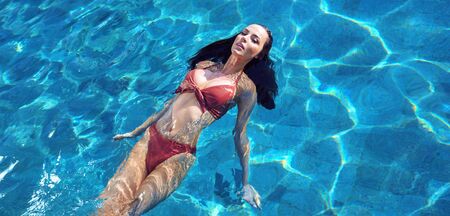 Sensual brunette woman relaxing in the tropical, luxurious poolの写真素材