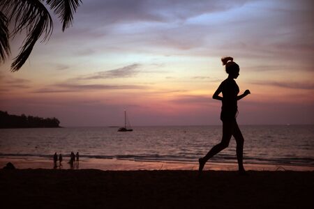 Young, fit woman doing jogging on a tropical beachの写真素材