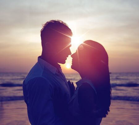 Romantic portrait of a young, attractive couple with fabulous sunset in backgroundの写真素材