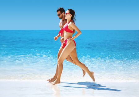 Fit couple doing jogging on a hot, tropical beachの写真素材