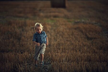 Adorable, little boy running on the corn fieldの写真素材