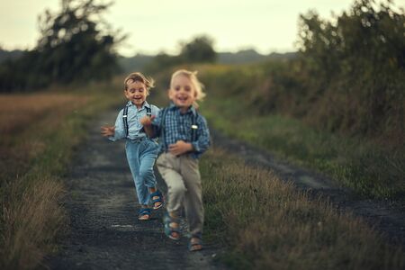 Two adorable brothers running on the country roadの写真素材