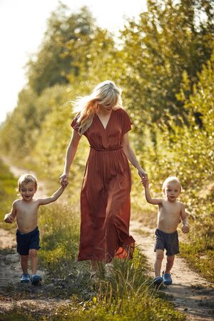 Cheerful, young mother walking with her two adorable twin-sonsの写真素材