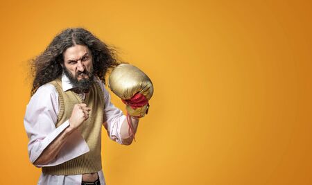 Portrait of a dangerous skinny nerd wearing a golden boxing glove