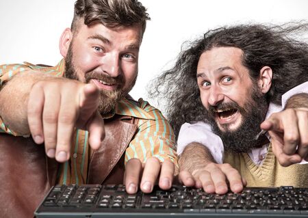 Closeup portrait of two geeks pointing a notebook screenの写真素材