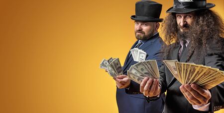 Two calm, successful businessmen holding a bunch of dollarsの写真素材