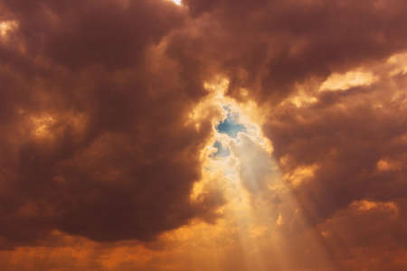 Cloudy orange sky with points of translucent sun rays