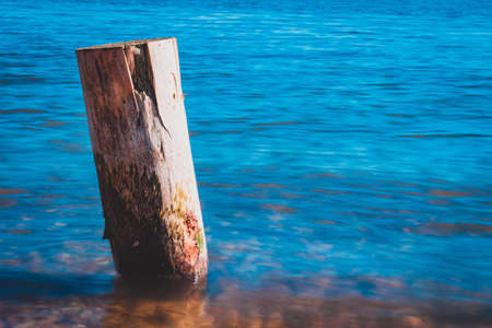 Wooden pile washed by the blue waters of the lake with the mountains in the background