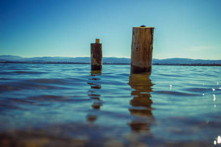 two wooden piles washed by the waters of the lake with the mountains in the background