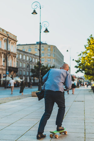 man in business attire riding a skateboard through the streets of the cityの写真素材