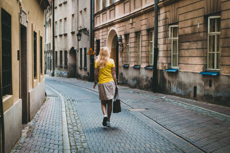 Modern woman in yellow t-shirt, walking by the old streets of Warsawの写真素材