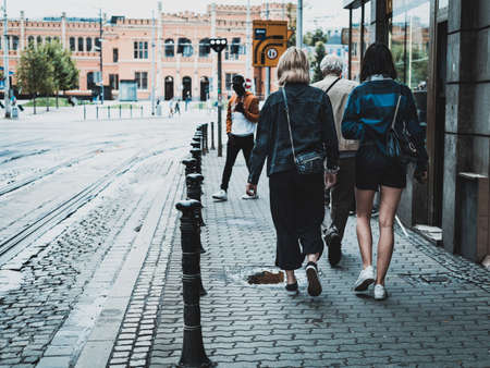 people on the streets of polish city, train station in the background
