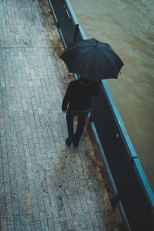 man with umbrella, view from above, city riverside boulevards