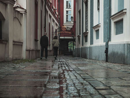 people in narrow passage between buildings, view from behind, streets after the rainの写真素材