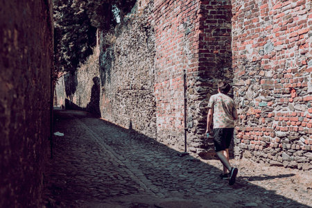 man in summer clothes on the stone path, old town walls