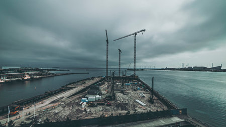 cranes at the construction site by the waterの写真素材