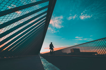silhouette of the cyclist on the bridge, person riding through the bridgeの写真素材