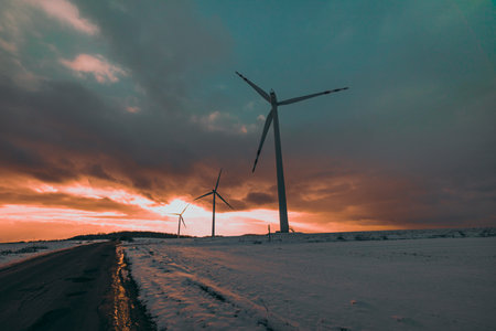windmills in a snowy field at sunsetの写真素材