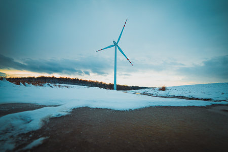frozen puddle on snowy fields with windmills in the backgroundの写真素材