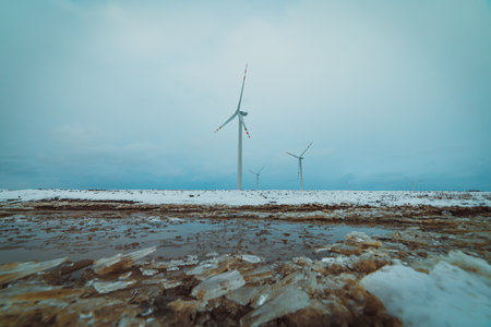 icy puddle on snowy fields with windmills in the backgroundの写真素材
