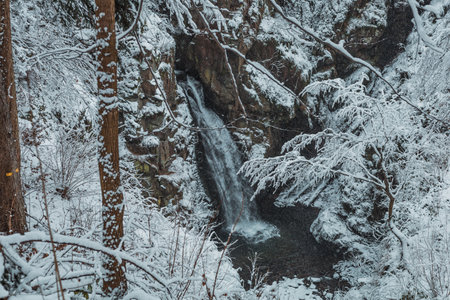 waterfall in snowy mountains during the winterの写真素材