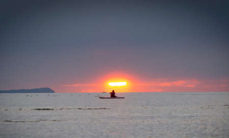 Silhouette of the girl on a surfboard at sunsetの写真素材