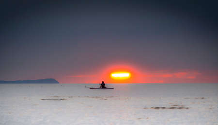 Silhouette of the girl on a surfboard at sunsetの写真素材