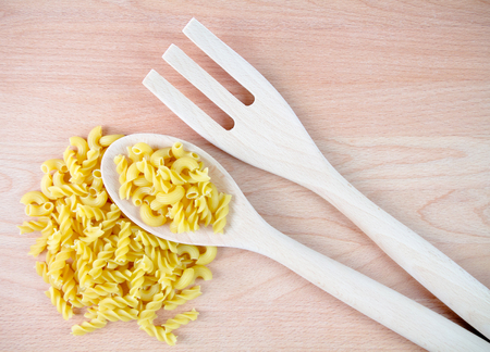 Spoon and fork with macaroni on wooden backgroundの写真素材