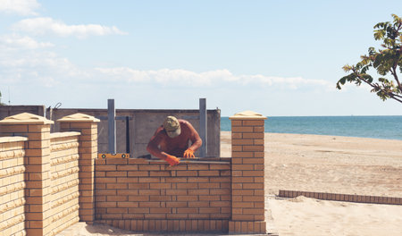 Builder builds a fence on the seashoreの写真素材