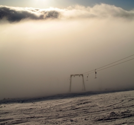 mountain   rope tow in fog  Over a fog dense clouds  Over clouds the sun shinesの写真素材