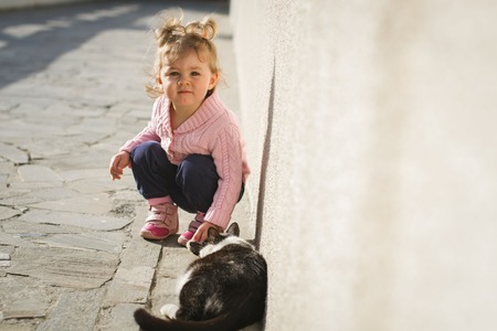 Little girl is playing with a big red cat in the country in Russia. Image with selective focus and toningの写真素材