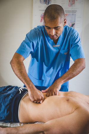 Macro close up of hands massaging female abdomen.Therapist applying pressure on belly.