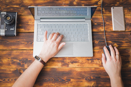 Male hands working on a white laptop on a wooden desktop and copy space at rightの写真素材