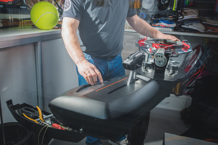 Stringing tennis racket on electric stringing machine