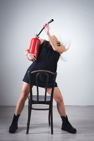Attractive tall woman in red dress with fire extinguisher in handの写真素材